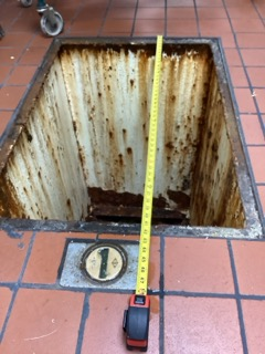 Tape measure spanning the inside width of an existing grease trap